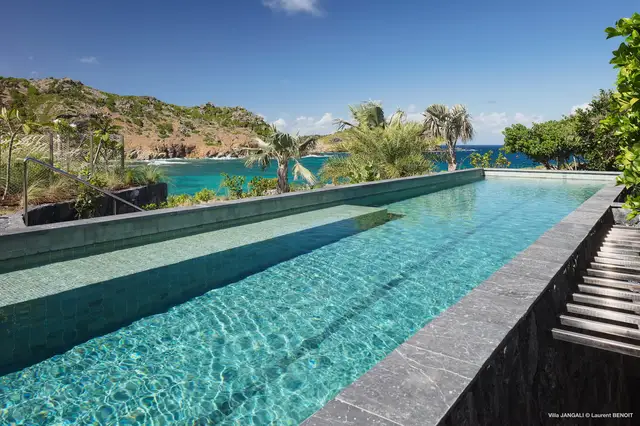 Infinity-edge pool with turquoise water overlooking rocky coast and ocean at Villa Jangali, Flamands