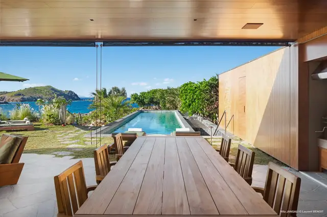 Covered dining area overlooking pool and ocean with distant hills at Villa Jangali, Flamands