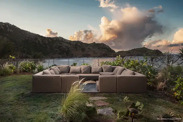 Outdoor sectional sofa on grassy terrace overlooking ocean and hills at Villa Jangali, Flamands