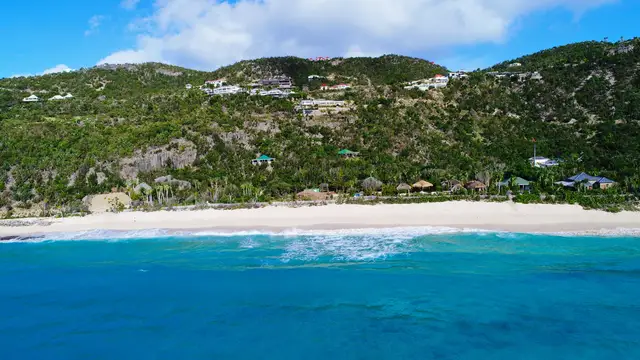Aerial view of beach, turquoise water, and hillside with buildings at Villa Krystel, Lurin