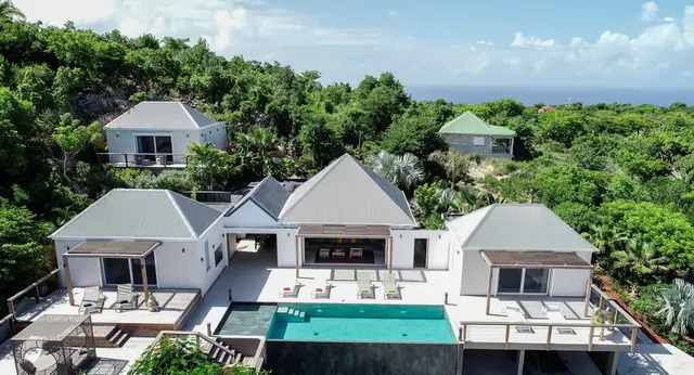 Multiple white buildings with gray roofs around turquoise pool at Villa Krystel, Lurin