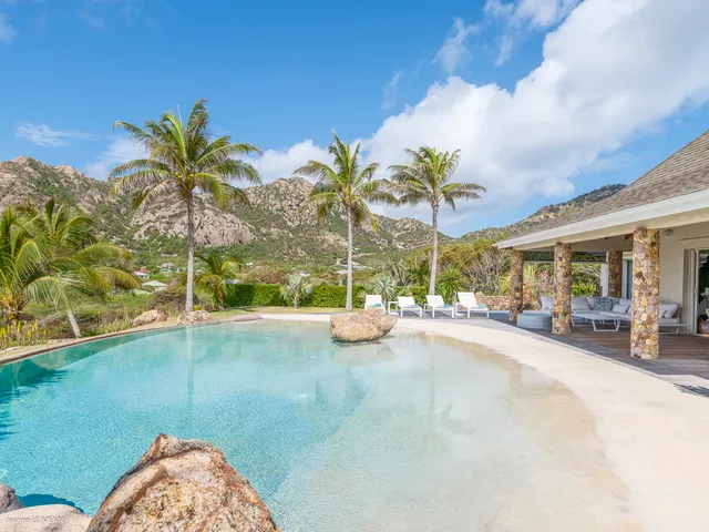 Curved pool with stone columns patio and lounge chairs overlooking hillside at Villa La Roche dans l’Eau, Grand Fond