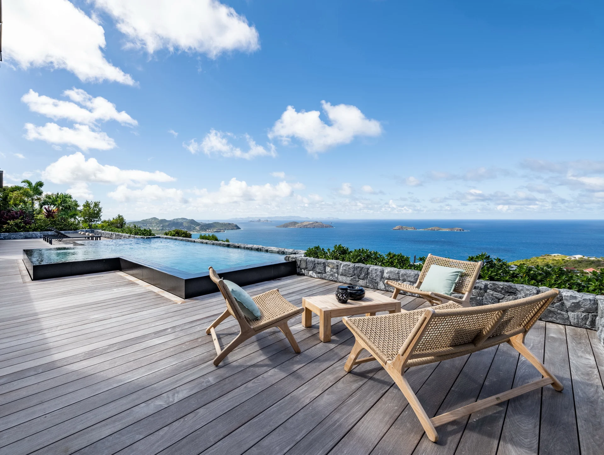 Infinity pool on wooden deck with lounge chairs overlooking ocean and islands at Villa Ma’O, Vitet