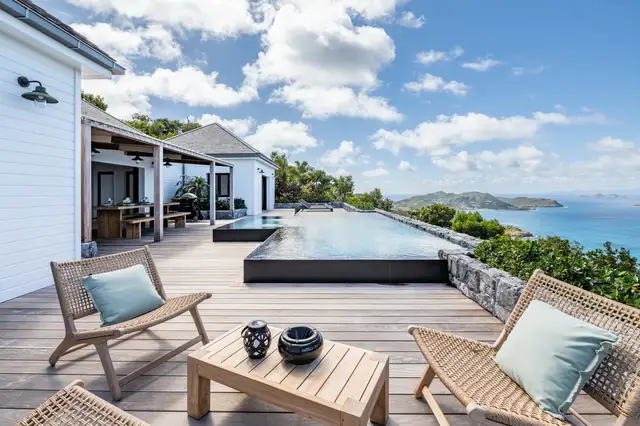 Wicker lounge chairs and coffee table near pool overlooking ocean at Villa Ma’O, Vitet