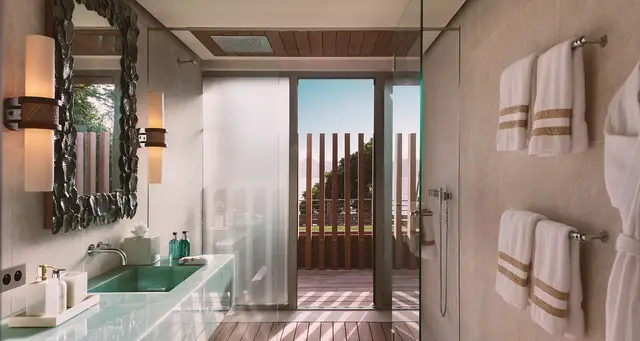 Bathroom with glass shower and teal vanity overlooking hills at Villa Nougat, Pointe Milou