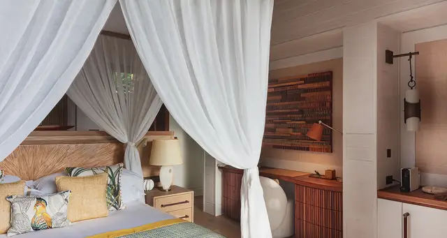 Bedroom with four-poster bed, desk, and wooden paneling at Villa Nougat, Pointe Milou