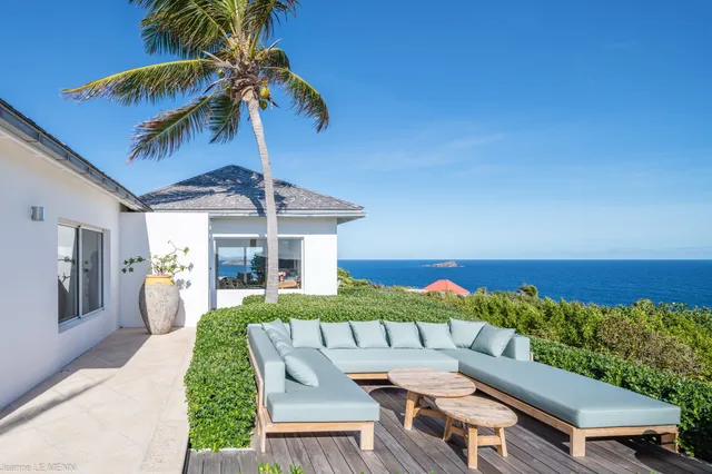 Wooden deck with outdoor sofa and tables overlooking ocean at Villa Poppy, Mont Jean