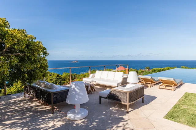 Terrace with seating and infinity pool overlooking ocean and island at Villa Poppy, Mont Jean